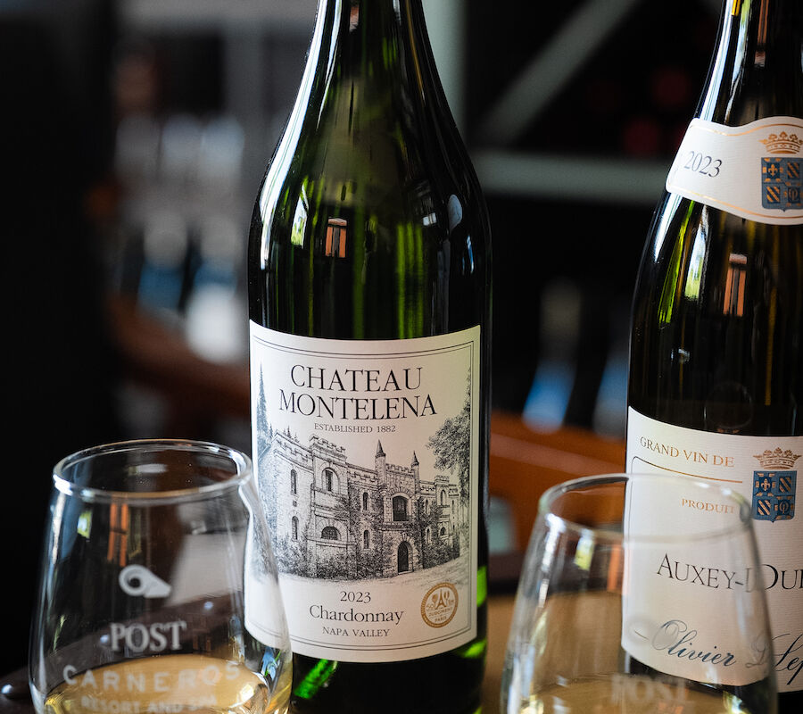 Two wine bottles and glasses on a table, featuring Château Montelena.