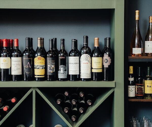 The image shows shelves with a variety of wine bottles, including red and white wines, arranged neatly in a display.