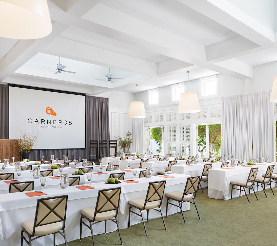 A conference room set up with tables and chairs, large screen displaying 