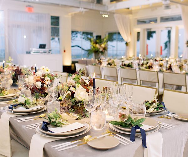 This image shows a beautifully decorated banquet hall with elegant table settings, floral centerpieces, and arranged dining tables ready for a formal event.