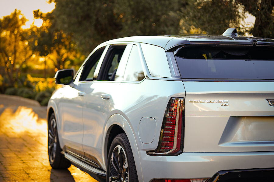 A white SUV is parked on a sunlit road surrounded by greenery, capturing a serene late afternoon vibe.