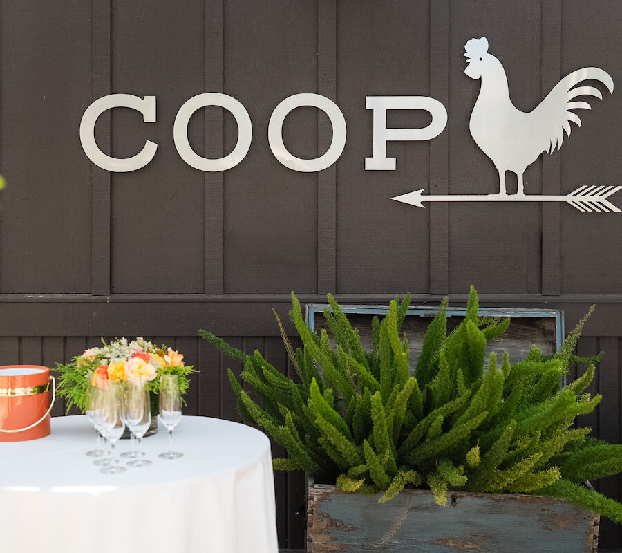 A table with flowers and drinks near a wooden wall labeled 