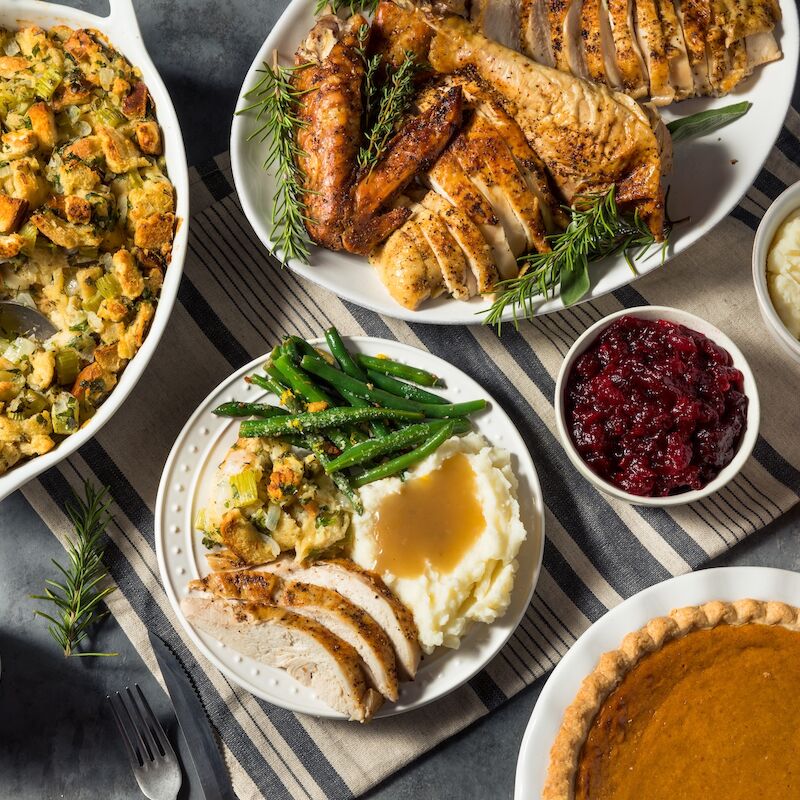 A Thanksgiving meal with roasted turkey, stuffing, mashed potatoes, cranberry sauce, green beans, and pumpkin pie.