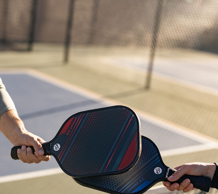 Two people on a pickleball court touching paddles over the net, symbolizing sportsmanship and fair play.